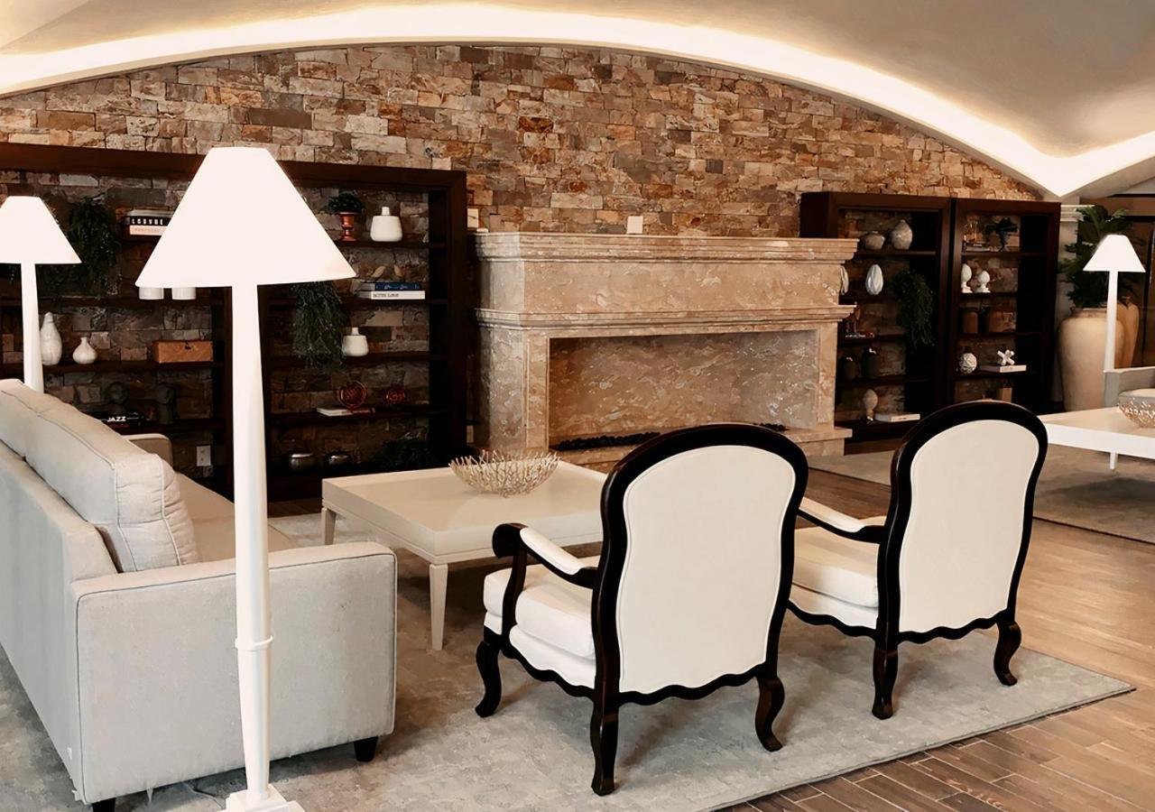 Buona Vitta Gramado Resort & Spa By Gramado Parks Exteriör bild The photo shows a stylish living room with a modern design. In the center, there is a light-colored sofa and two elegant white armchairs with black wooden frames. A coffee table is placed in front of the sofa. Behind them, there is a large, decorativ
