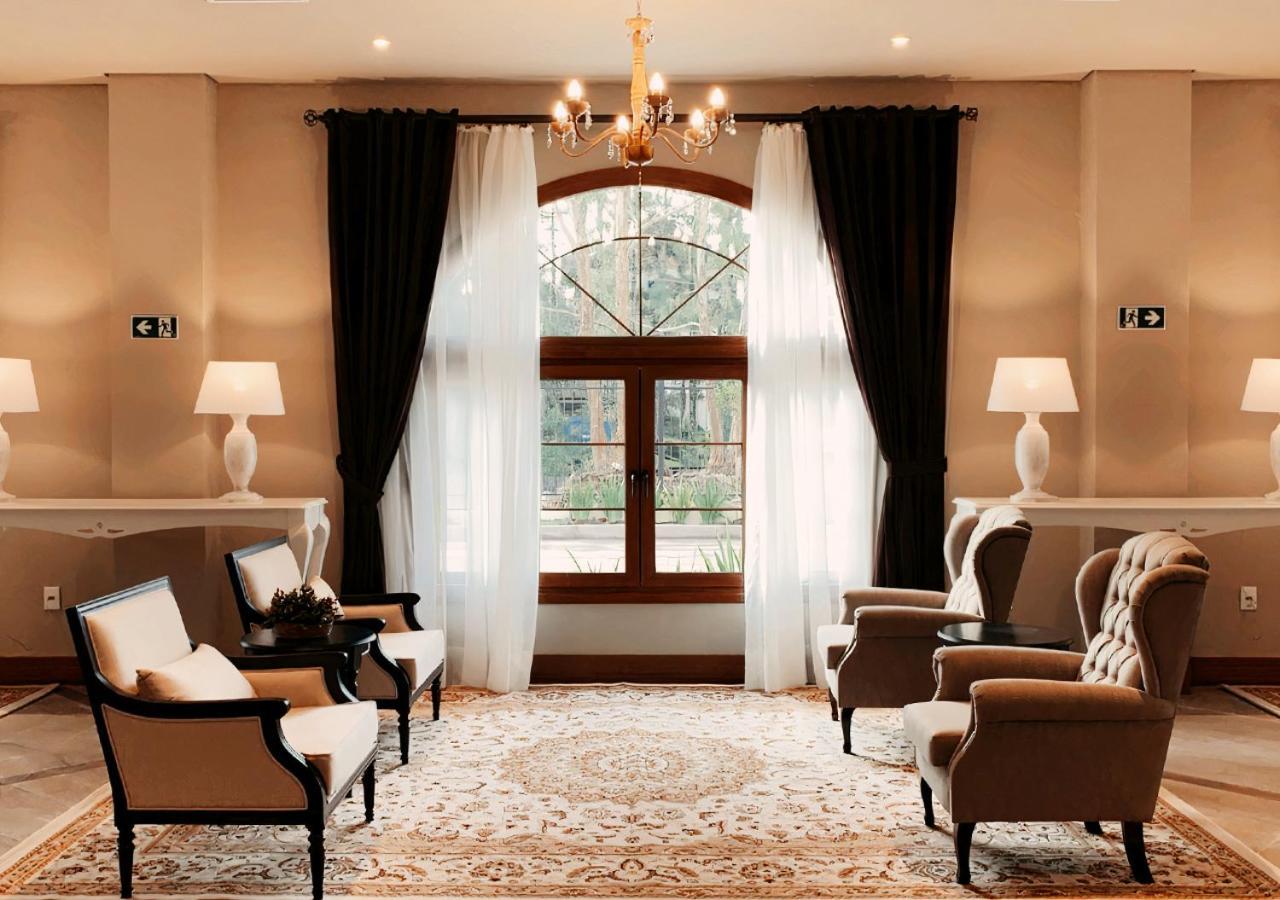 Buona Vitta Gramado Resort & Spa By Gramado Parks Exteriör bild The photo shows an elegantly styled living room. There are two armchairs and a sofa arranged comfortably around an intricate area rug. Large windows are adorned with sheer white curtains and dark curtains, allowing natural light to fill the space. A 