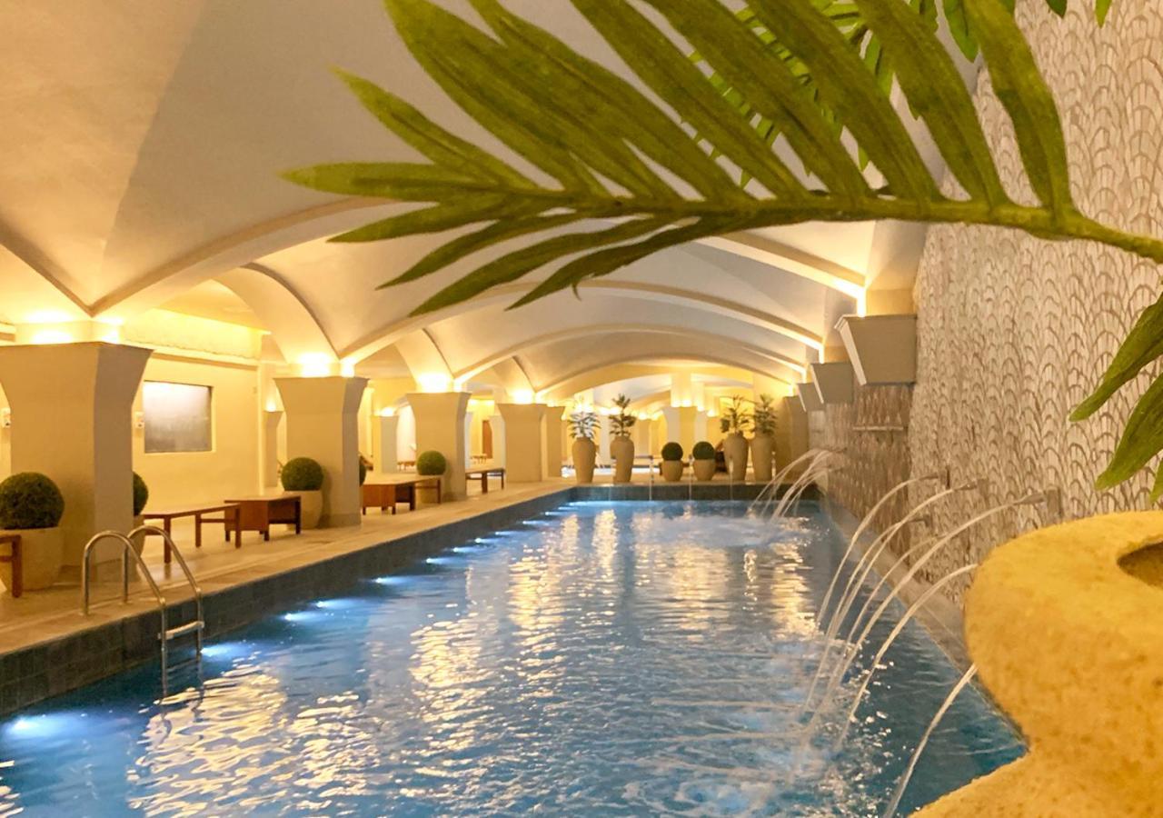 Buona Vitta Gramado Resort & Spa By Gramado Parks Exteriör bild The photo shows an indoor swimming pool with a serene and elegant atmosphere. The pool has a calm blue water surface, illuminated by soft lights along its edges. The architectural design features arches in the ceiling, creating an open and spacious f