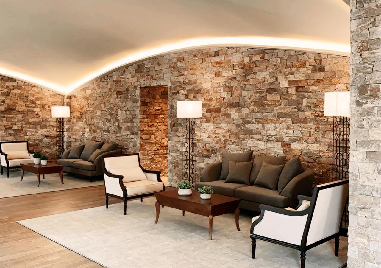 Buona Vitta Gramado Resort & Spa By Gramado Parks Exteriör bild The photo shows a stylish and modern lounge area. The walls are made of natural stone, creating a warm and inviting atmosphere. There are two comfortable sofas in a muted gray color arranged around a wooden coffee table. Flanking the sofas are elegan