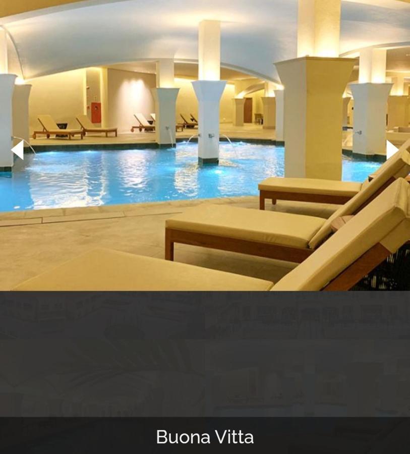 Buona Vitta Gramado Resort & Spa By Gramado Parks Exteriör bild The photo shows a tranquil indoor pool area, featuring a large swimming pool with clear blue water. Surrounding the pool are several lounge chairs made of light-colored wood, positioned for relaxation. The space is well-lit, with soft lighting highli