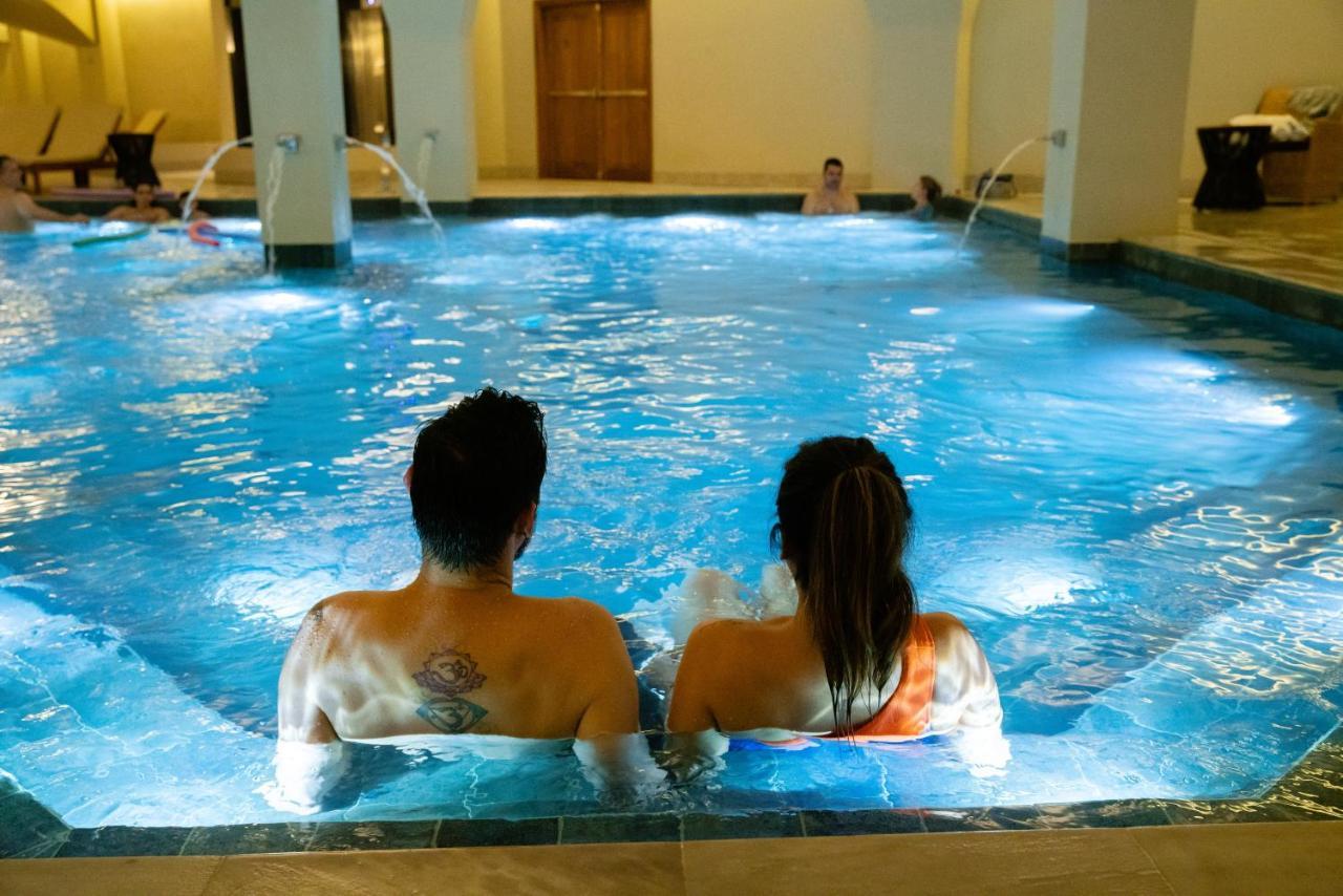Buona Vitta Gramado Resort & Spa By Gramado Parks Exteriör bild The photo shows a couple sitting in a swimming pool with gentle lighting. They are facing away from the camera, appearing relaxed and enjoying their time together. The water is illuminated with a soft blue light, creating a serene atmosphere. In the 