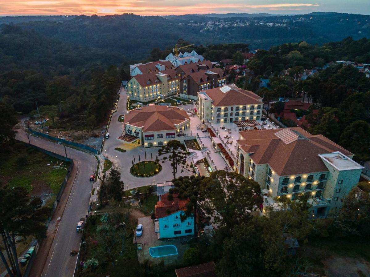 Buona Vitta Gramado Resort & Spa By Gramado Parks Exteriör bild The photo shows an aerial view of a hotel complex set in a hilly, wooded area. The buildings feature a mix of architectural styles with several structures, including a central round pavilion. Surrounding the buildings are well-maintained gardens and 
