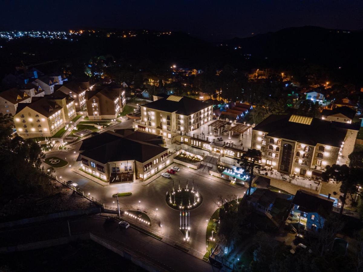 Buona Vitta Gramado Resort & Spa By Gramado Parks Exteriör bild The photo shows a beautifully lit resort or hotel complex taken at night. The buildings are well-illuminated, highlighting their architecture. There is a circular area with a fountain at the center, surrounded by pathways that connect various parts o