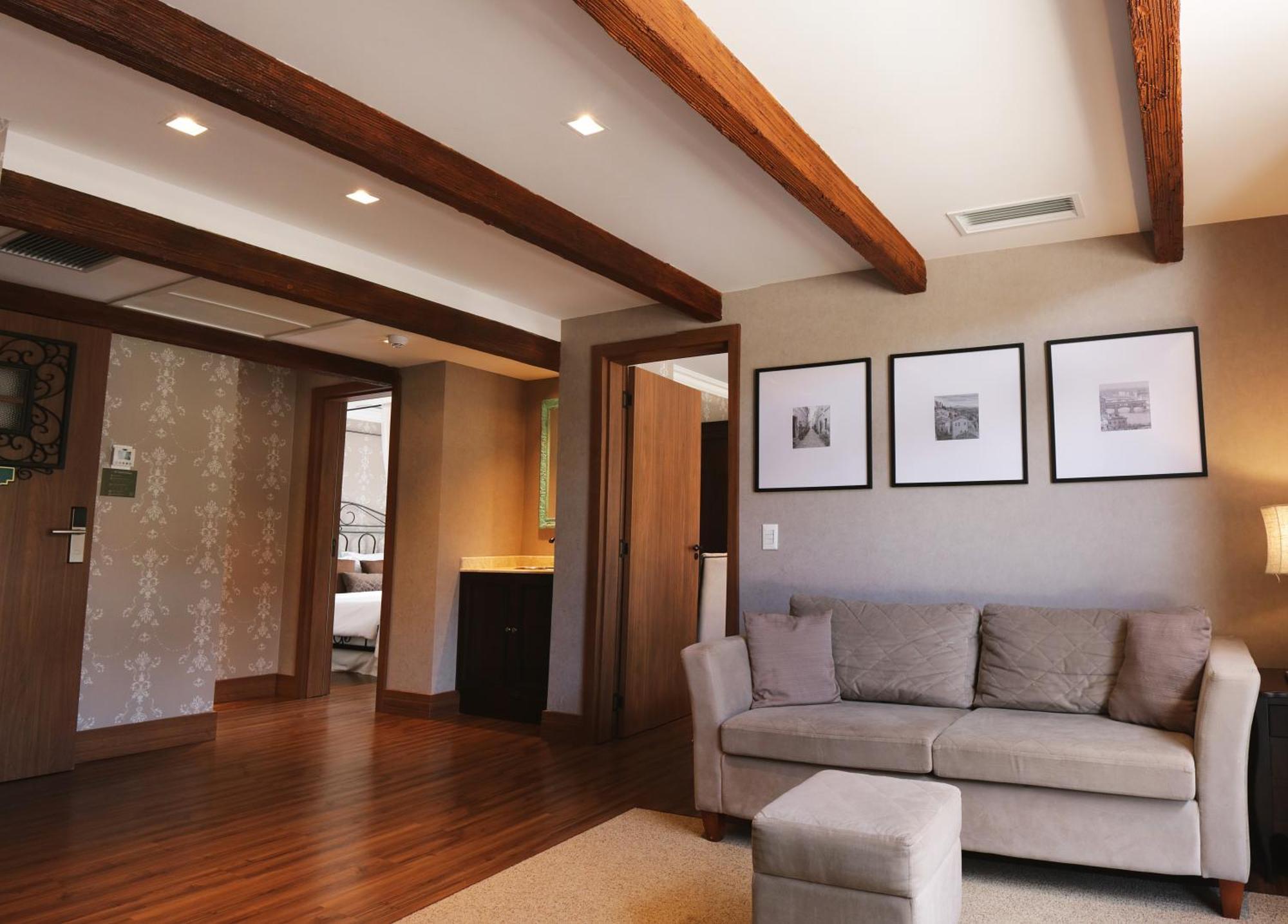 Buona Vitta Gramado Resort & Spa By Gramado Parks Exteriör bild The photo showcases a modern living space with a cozy and well-lit atmosphere. There are wooden beams visible on the ceiling, adding a rustic touch. The flooring is a warm-toned wood, contributing to the inviting feel of the room. 

On one side, ther