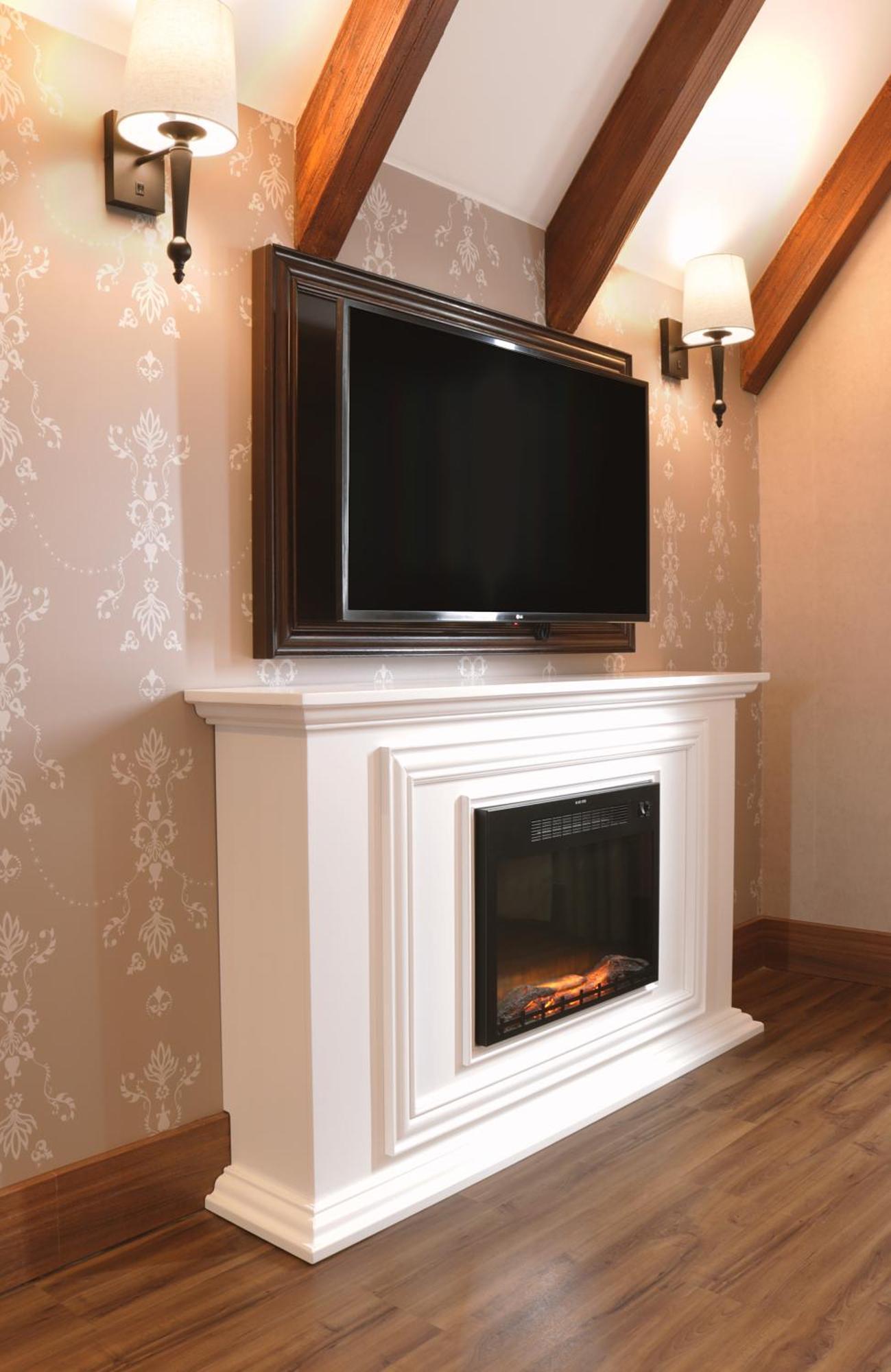 Buona Vitta Gramado Resort & Spa By Gramado Parks Exteriör bild The image shows a modern living room setup featuring a white mantel with an electric fireplace. Above the mantel, there is a large flat-screen television mounted on the wall. The fireplace has a glass front and displays a realistic flame effect, crea